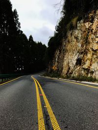 Road by trees against sky