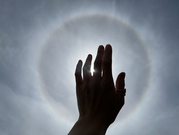 Close-up of human hand against sky