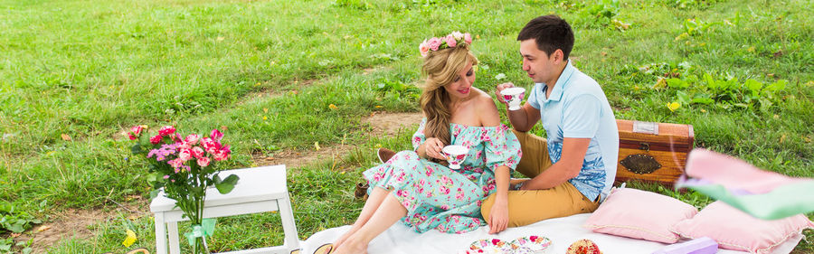 Rear view of two women sitting on grassy field