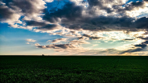 Scenic view of agricultural field against dramatic sky