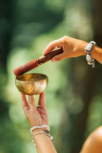 Woman playing on tibetan singing bowl in the forest