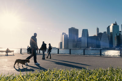 Silhouetted people on the waterfront with lower manhattan skyline  the east river in late afternoon.