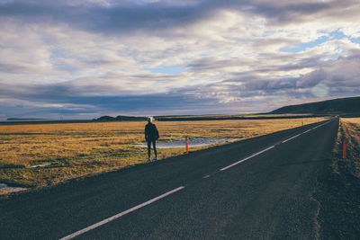 Rear view of man walking on country road