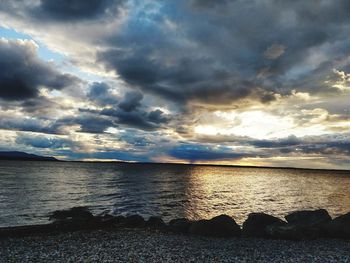 Scenic view of sea against cloudy sky during sunset