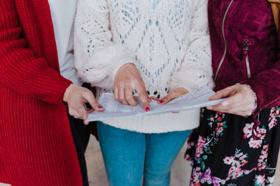 Midsection of women holding map at home