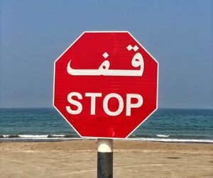 Close-up of warning sign on beach against clear sky