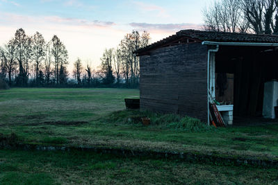 House and trees on field against sky