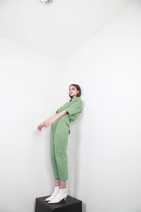 Full length portrait of teenage girl standing against wall