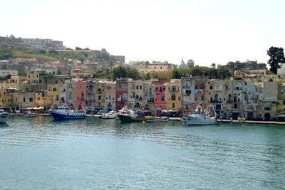 Boats moored in canal by buildings against sky