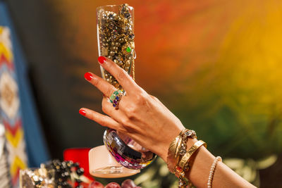 Cropped hand of woman holding glass with jewelry