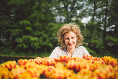 Portrait of smiling woman with orange tulips blooming at park