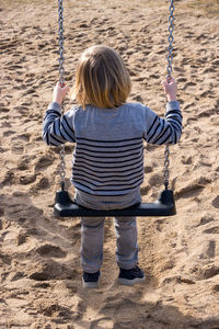 Rear view of girl on swing at playground
