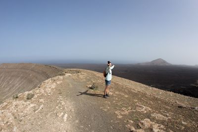 Full length of man standing on mountain against clear sky