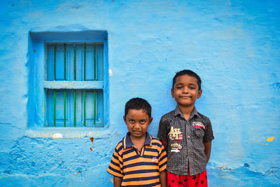 Portrait of smiling boy standing against blue wall