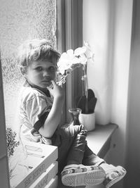 Portrait of boy sitting by window at home