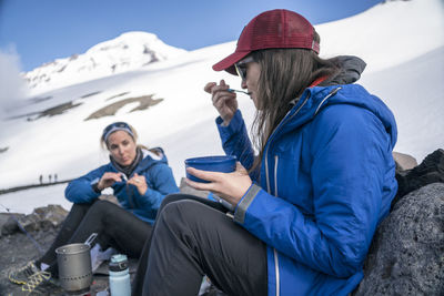 Two women eating breakfast and talking at base camp, mt. baker