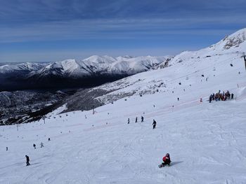 People skiing on snowcapped mountain against sky
