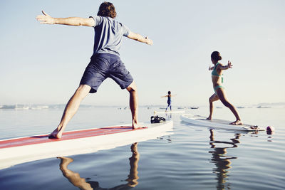 A group of standup paddle boarders doing yoga at sunrise in the fog