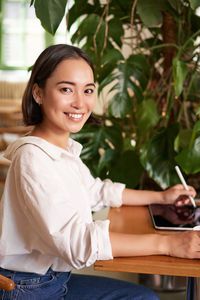 Portrait of smiling young woman sitting at home