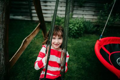 Portrait of smiling girl sitting on swing