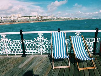 Chairs and table by sea against sky