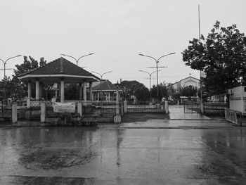 Building by wet road against sky during rainy season