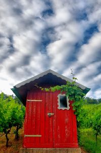 Low angle view of red house on field against sky