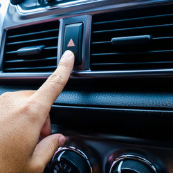 Cropped hand pushing air conditioner button in car