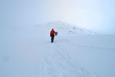 Rear view of people hiking on snowcapped mountain