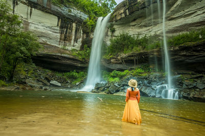 Woman standing by waterfall in forest