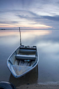 Boat moored on beach against sky during sunset