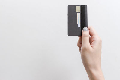 Close-up of hand holding smart phone over white background