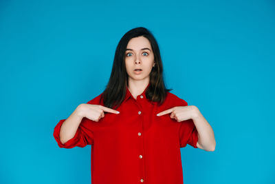 Portrait of young woman standing against blue background