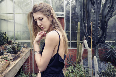 Beautiful young woman looking down while sitting on tree