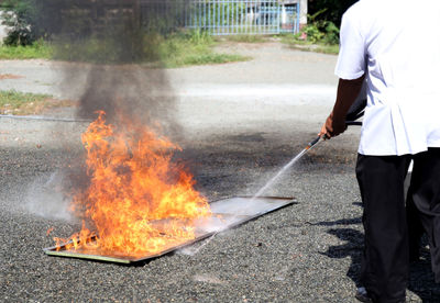 Midsection of man with fire on road