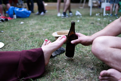 Man holding bottle while sitting with woman in park