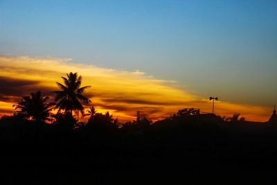 Silhouette trees on landscape against sky at sunset