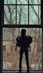 Rear view of man looking through window