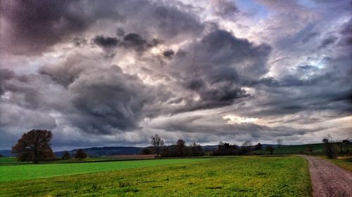 Scenic view of field against storm clouds