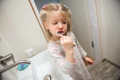 Girl brushing teeth in bathroom at home