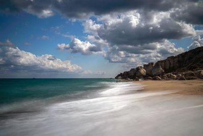 Scenic view of beach against cloudy sky