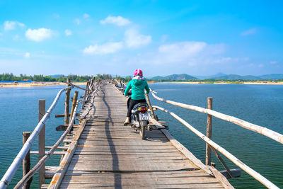 Rear view of man riding bicycle on pier
