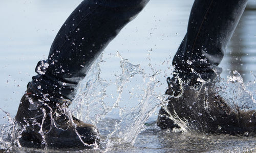 Low section of man walking in puddle