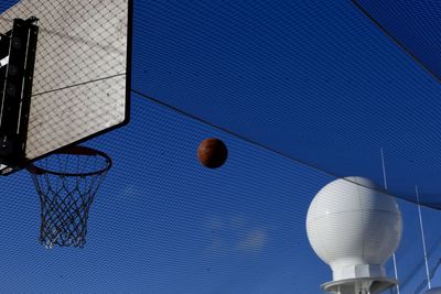 Low angle view of basketball hoop seen through net