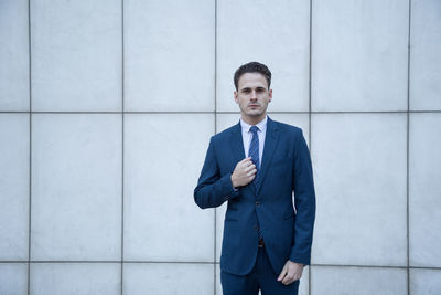 Portrait of young man standing against wall