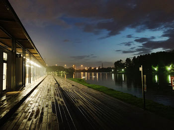 Illuminated city by river against sky at night