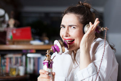 Portrait of woman screaming on old-fashioned telephone at home