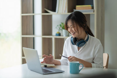 Woman using phone while sitting on table