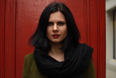 Close-up portrait of young woman standing against red wall