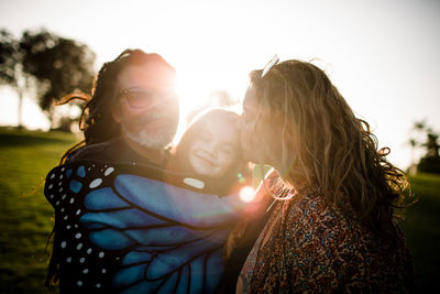 Aunt, uncle and niece hugging and posing during sunset